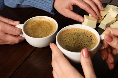 Photo of Women having coffee break at wooden table, closeup