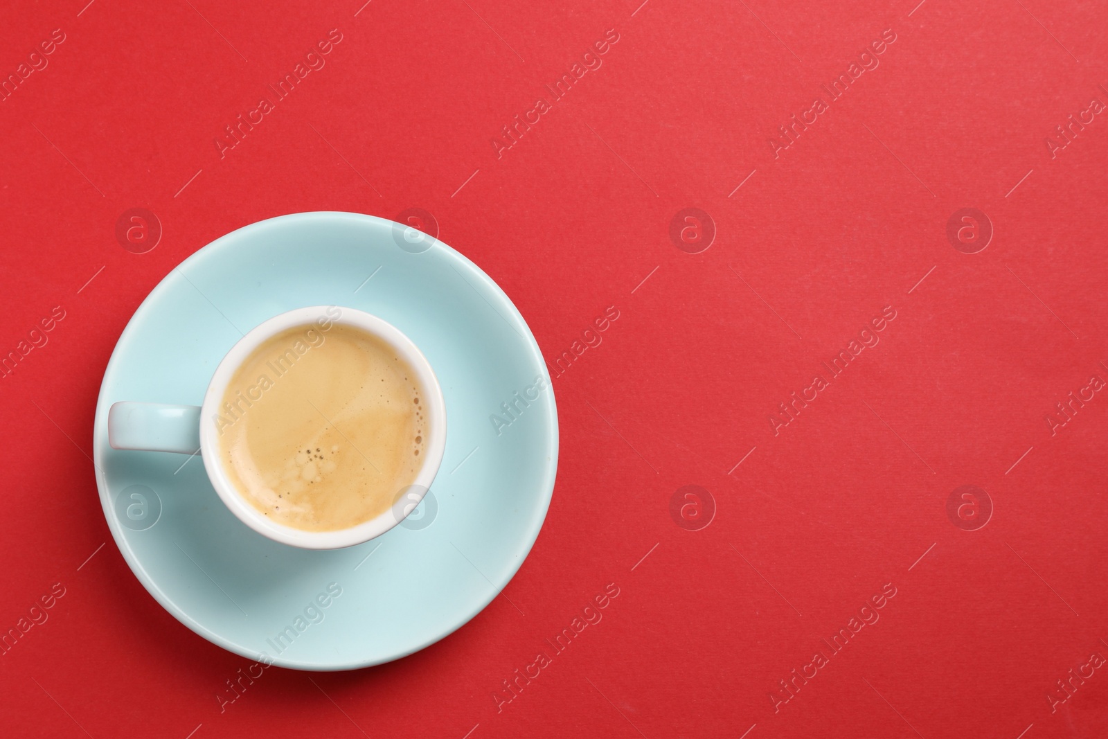 Photo of Aromatic coffee in cup on red background, top view. Space for text