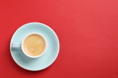 Photo of Aromatic coffee in cup on red background, top view. Space for text