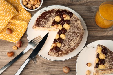 Photo of Delicious Kyiv Cake decorated with cream and hazelnuts served on wooden table, above view