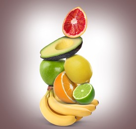 Stack of different fresh fruits on pale brown gradient background