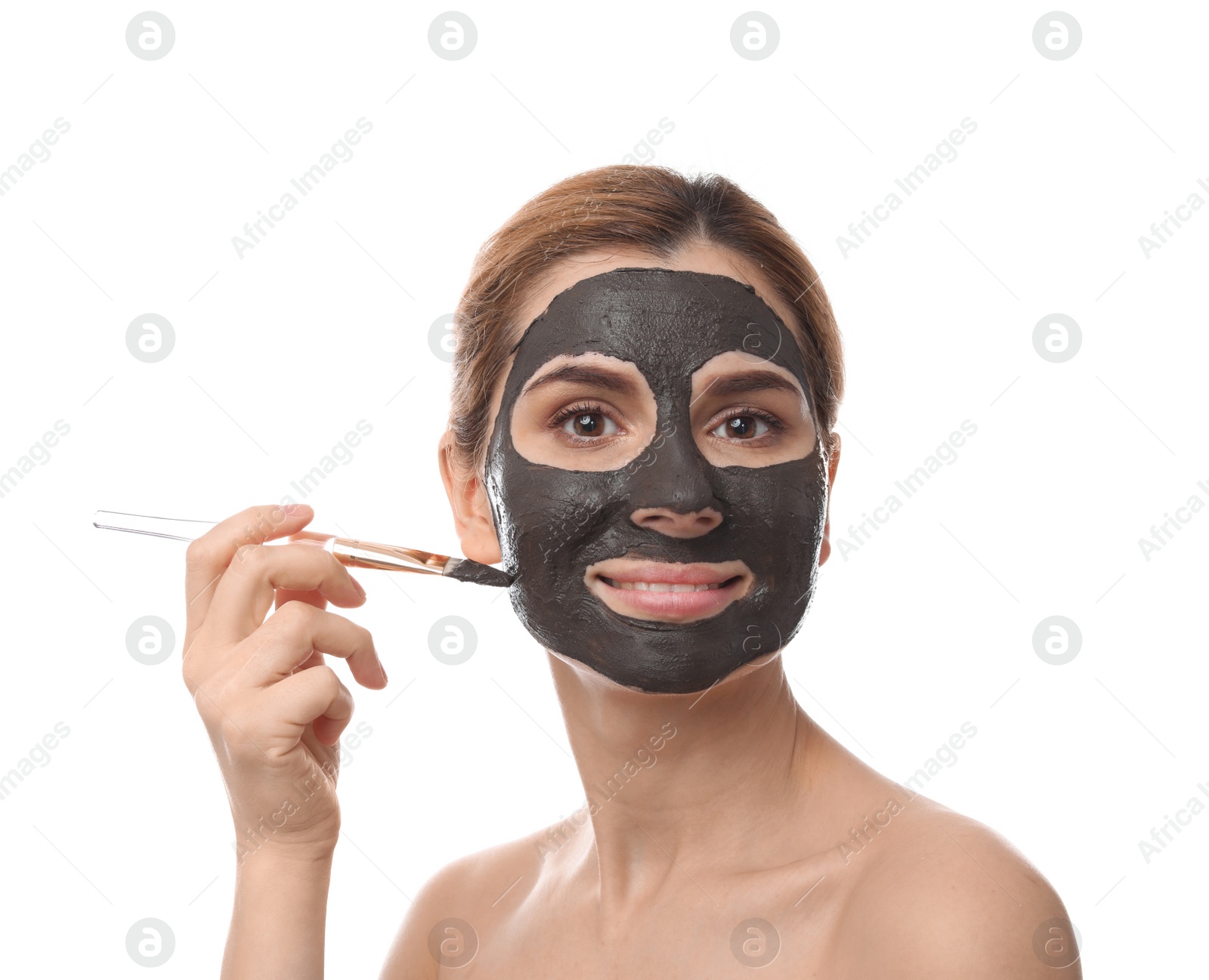 Photo of Beautiful woman applying black mask onto face against white background