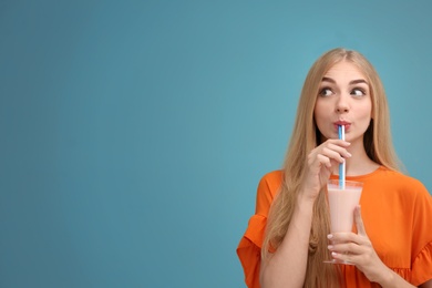 Young woman with glass of delicious milk shake on color background