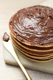 Photo of Delicious pancakes with chocolate paste and knife on table, closeup