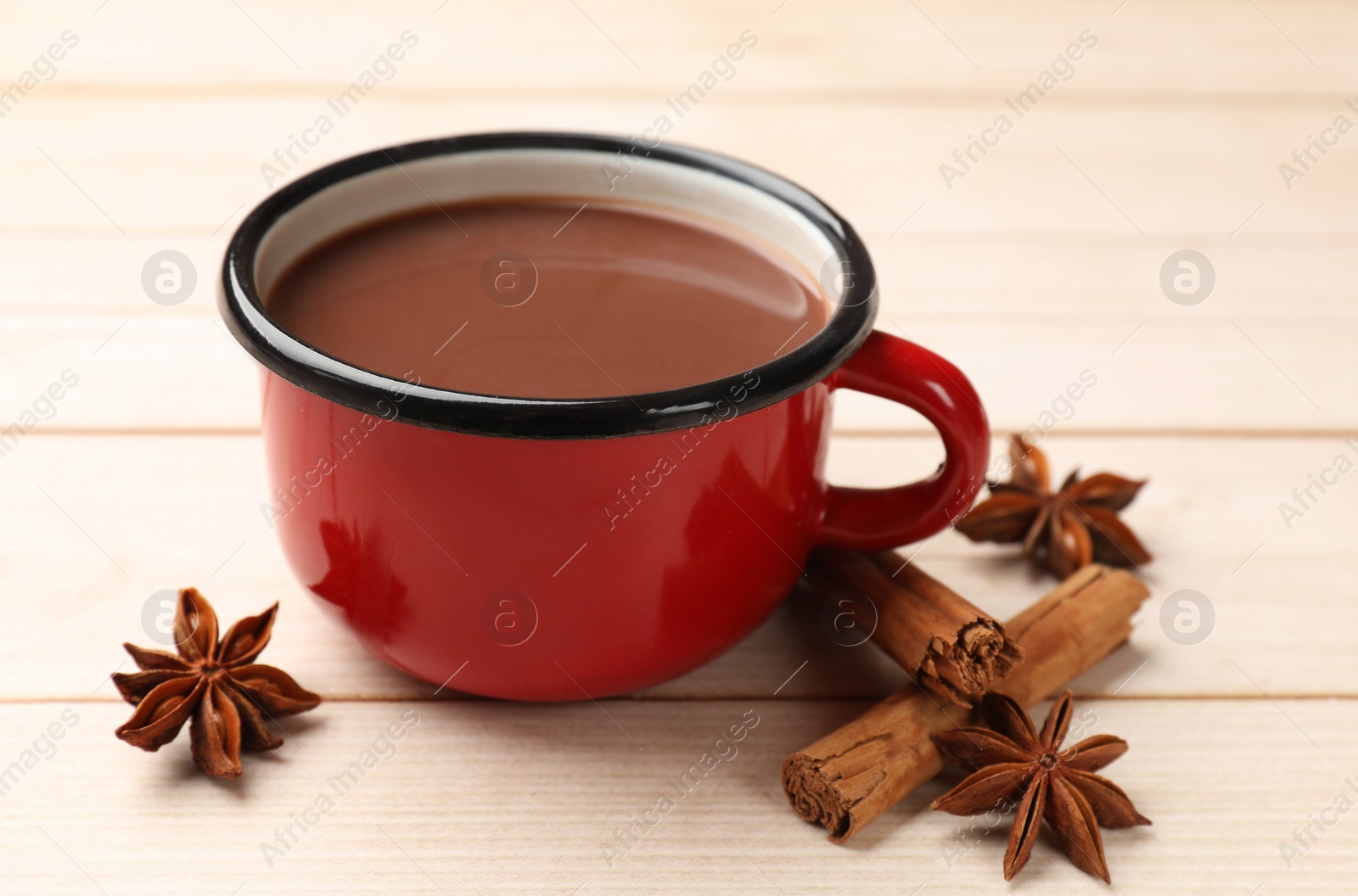 Photo of Tasty hot chocolate and spices on light wooden table, closeup