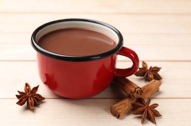 Photo of Tasty hot chocolate and spices on light wooden table, closeup