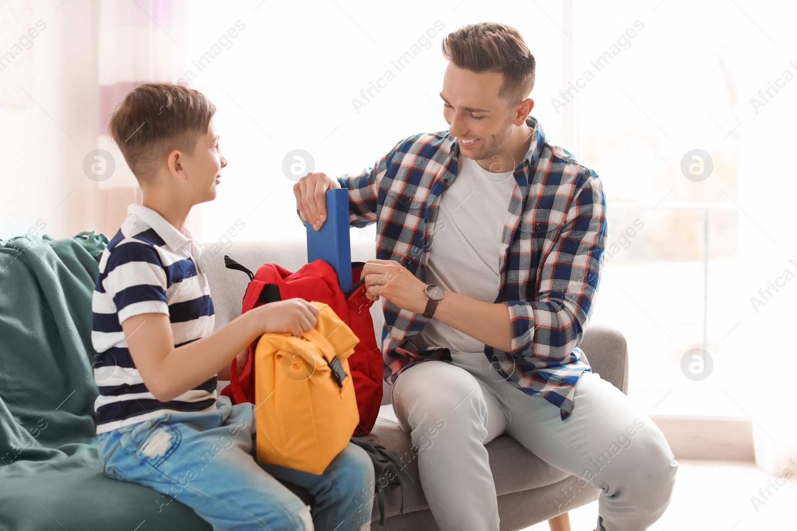 Photo of Young man helping his little child get ready for school at home