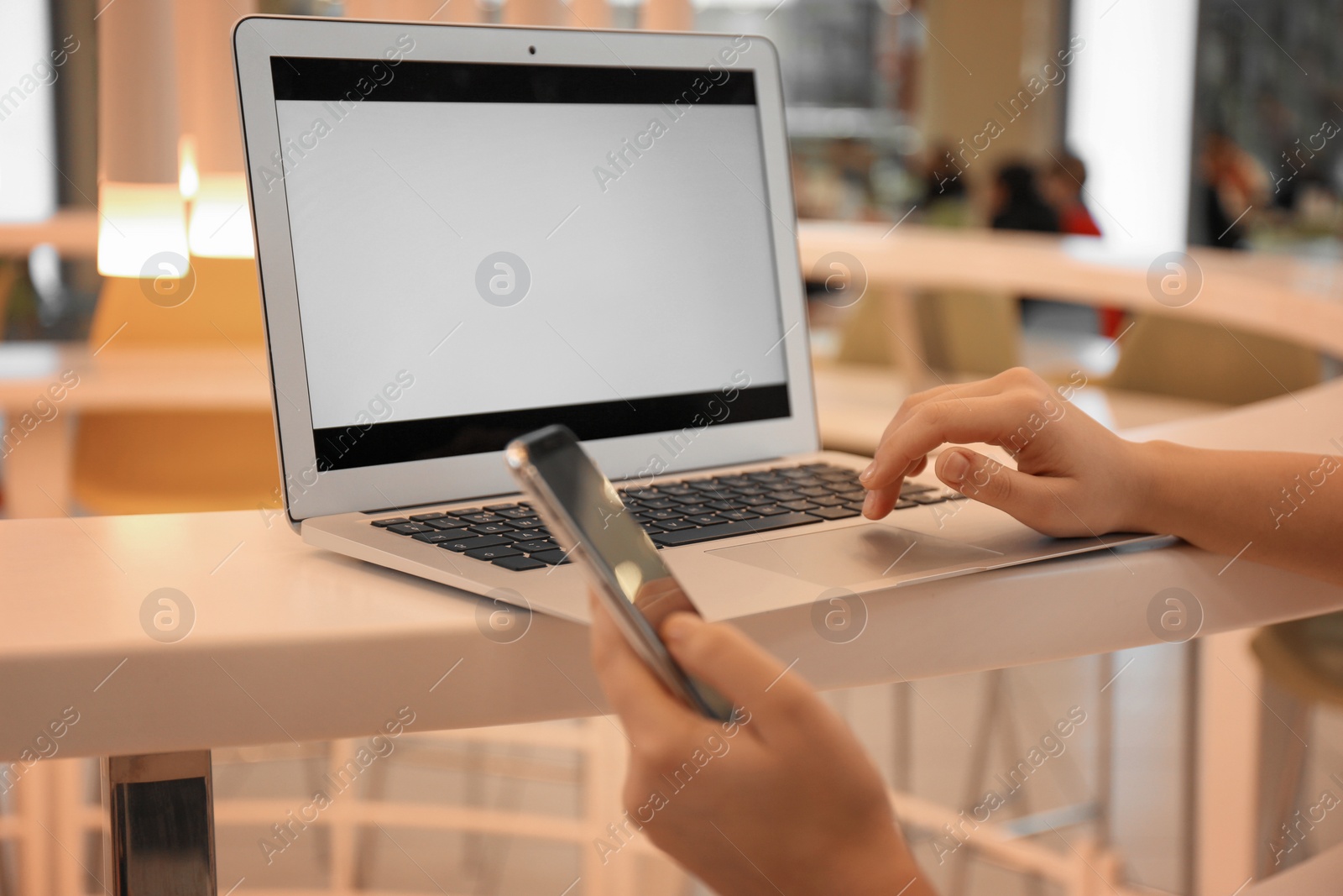 Photo of Blogger with laptop and mobile phone in cafe, closeup