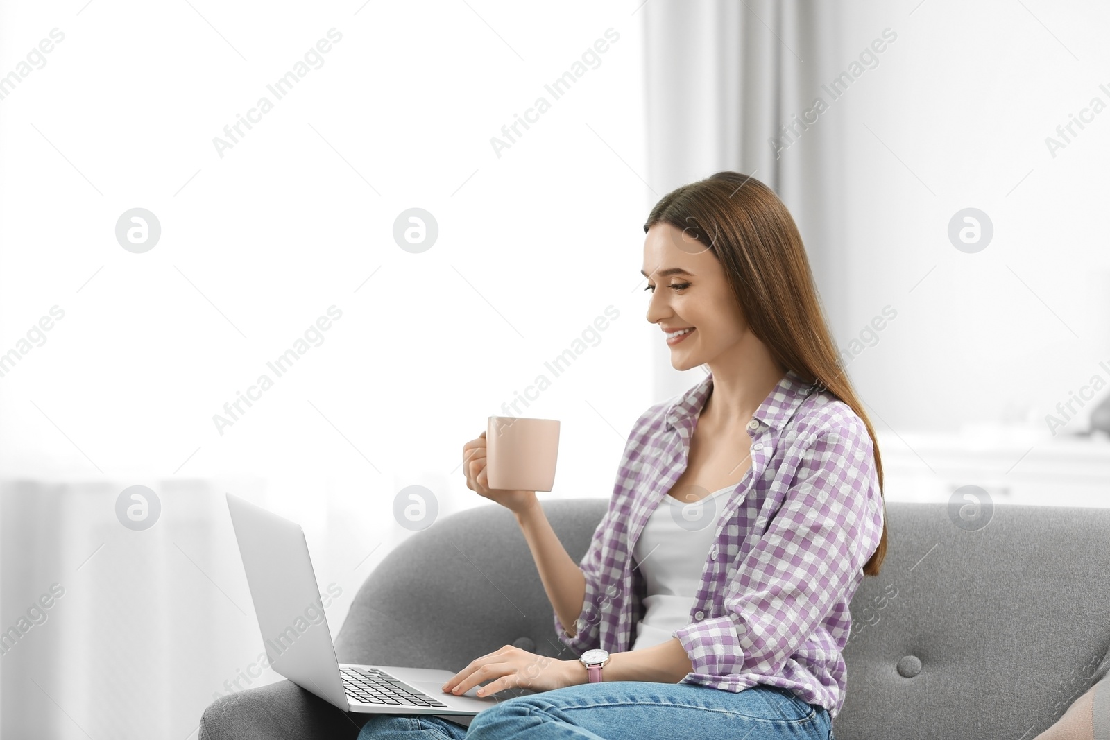 Photo of Young woman using modern laptop at home