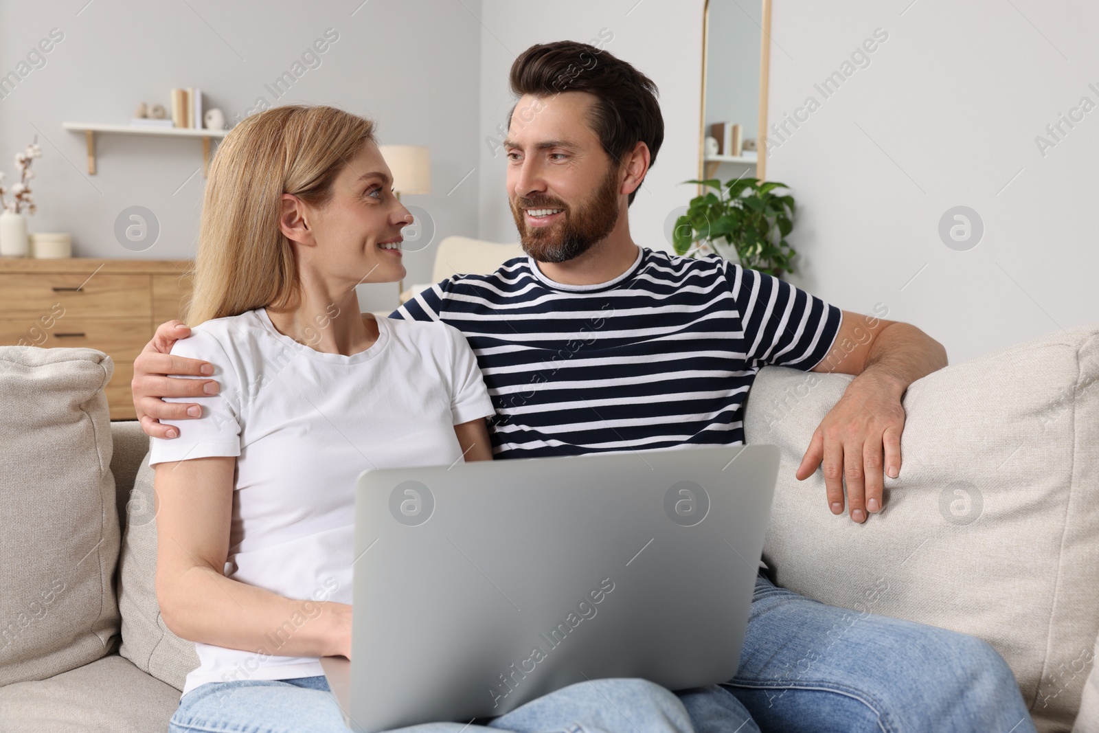 Photo of Happy couple with laptop on sofa at home