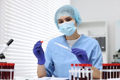 Photo of Laboratory testing. Doctor with blood samples in tubes at white table indoors