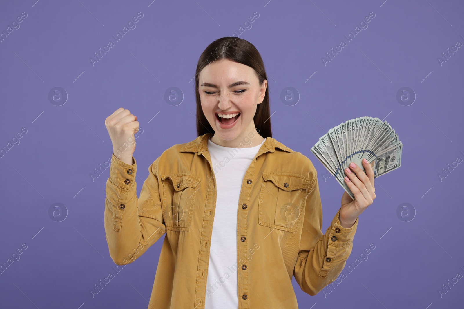 Photo of Excited woman with dollar banknotes on purple background