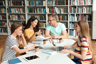 Young people discussing group project at table in library