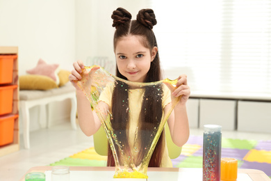 Photo of Little girl playing with slime in room