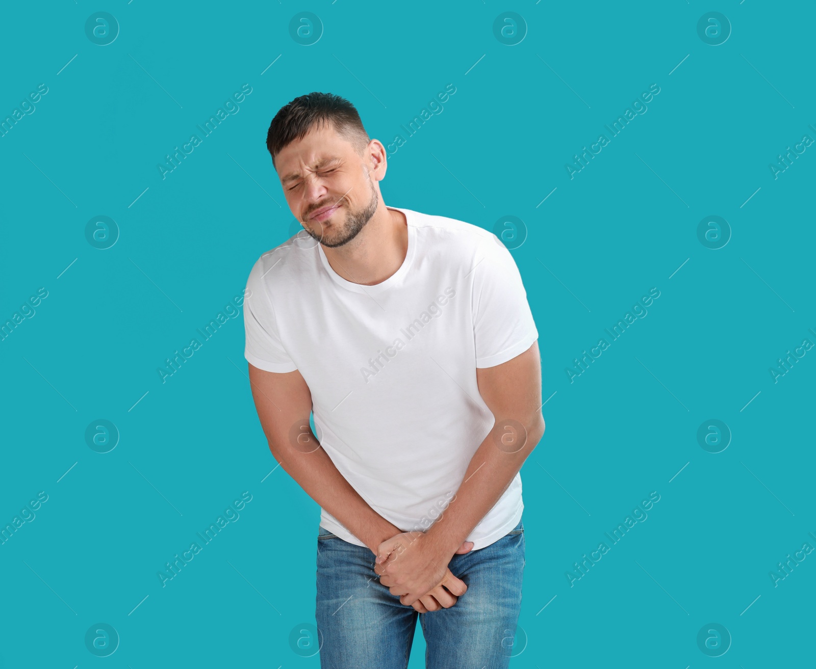 Photo of Man suffering from pain on turquoise background. Urology problems