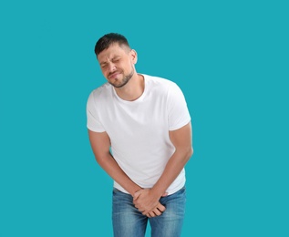 Man suffering from pain on turquoise background. Urology problems