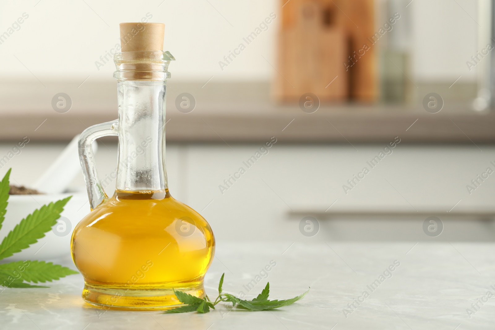 Photo of Hemp oil and leaves on light table against blurred background. Space for text