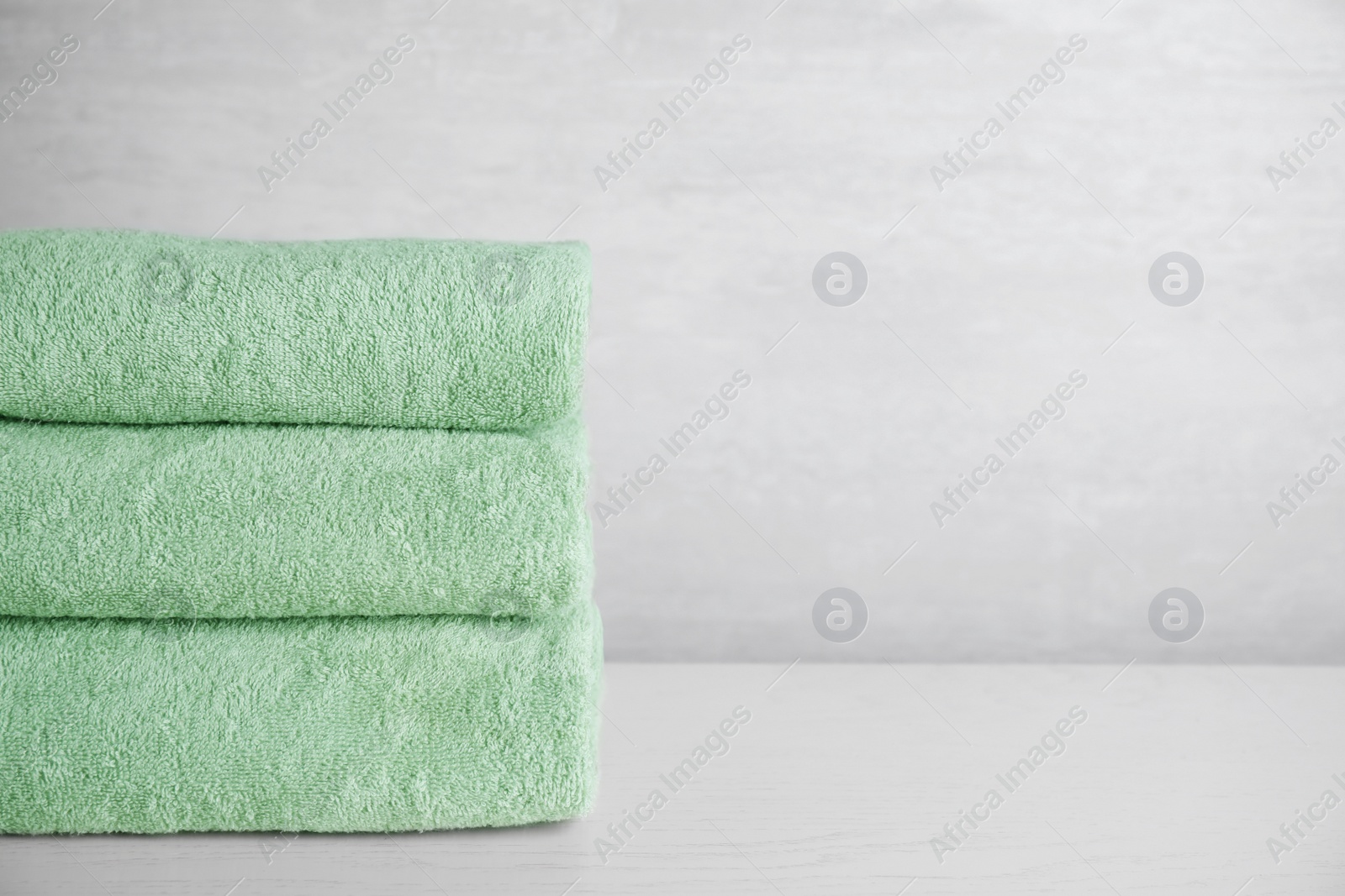 Photo of Stack of clean bath towels on white wooden table. Space for text