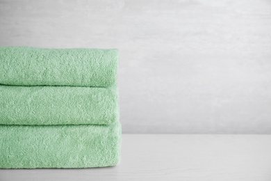 Photo of Stack of clean bath towels on white wooden table. Space for text