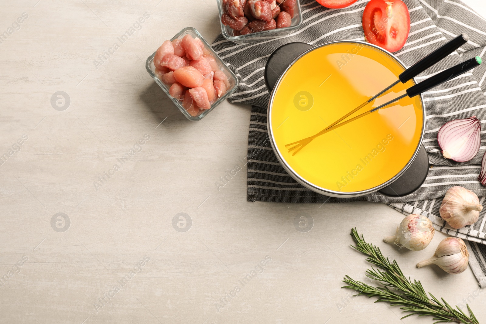 Photo of Flat lay composition with oil pot, meat fondue ingredients and space for text on light background