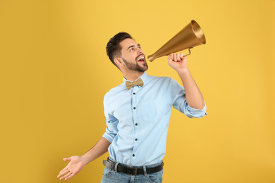 Photo of Young man with megaphone on yellow background