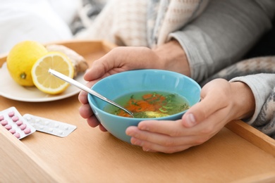 Sick young man eating soup to cure flu, closeup