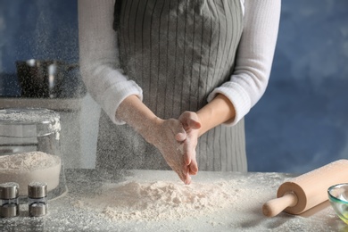 Photo of Woman sprinkling flour over table in kitchen