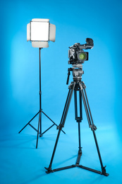 Professional video camera and lighting equipment on blue background