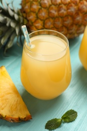 Photo of Delicious fresh pineapple juice on light blue wooden table