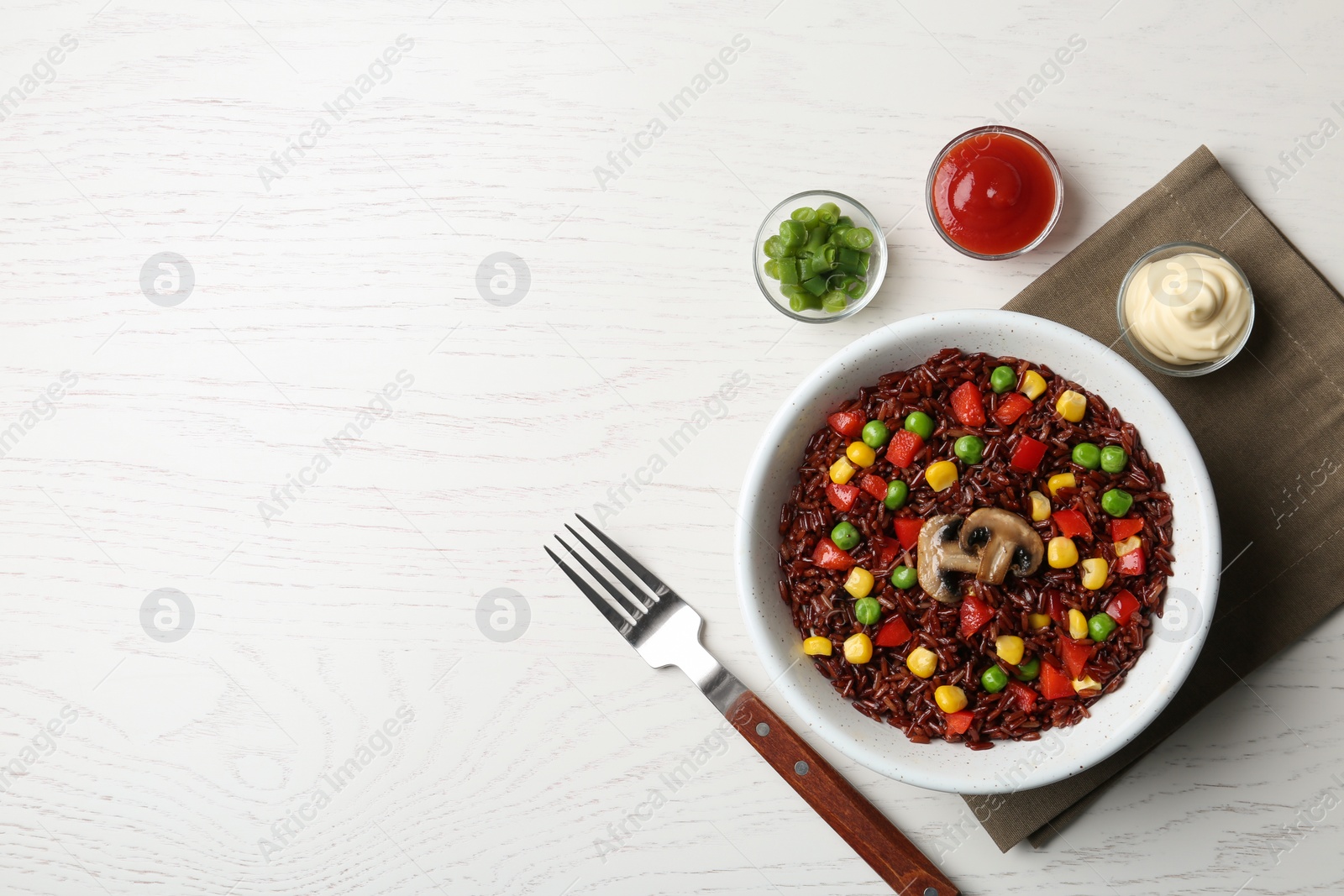 Photo of Bowl with cooked brown rice served on table, top view. Space for text