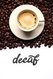 Photo of Word Decaf, cup of coffee and beans on white background, flat lay