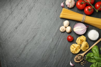 Different types of pasta, spices and products on dark textured table, flat lay. Space for text