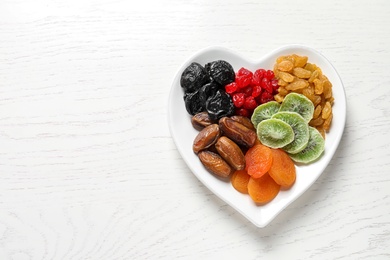 Photo of Plate of different dried fruits on wooden background, top view with space for text. Healthy lifestyle