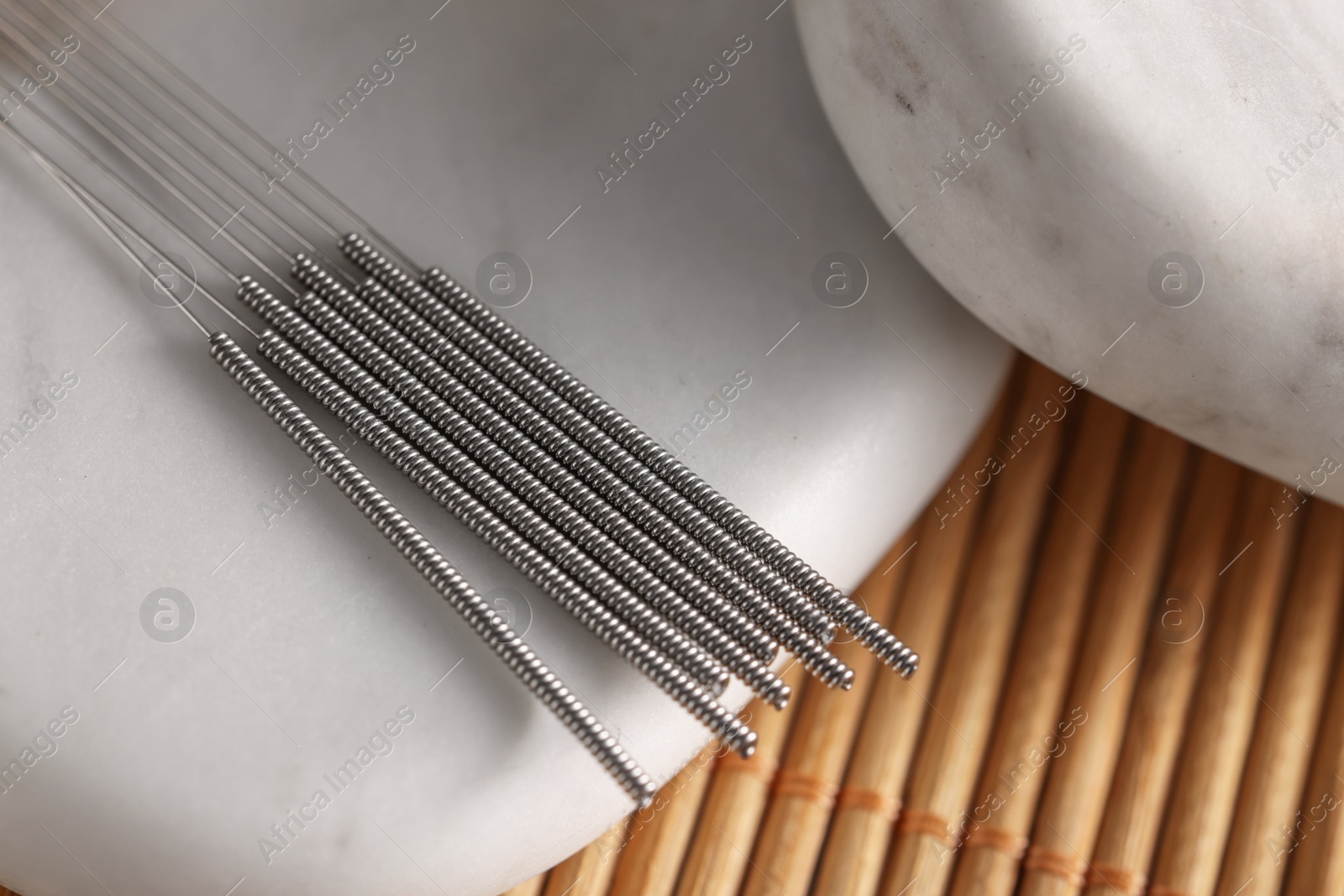 Photo of Acupuncture needles and spa stones on bamboo mat, above view