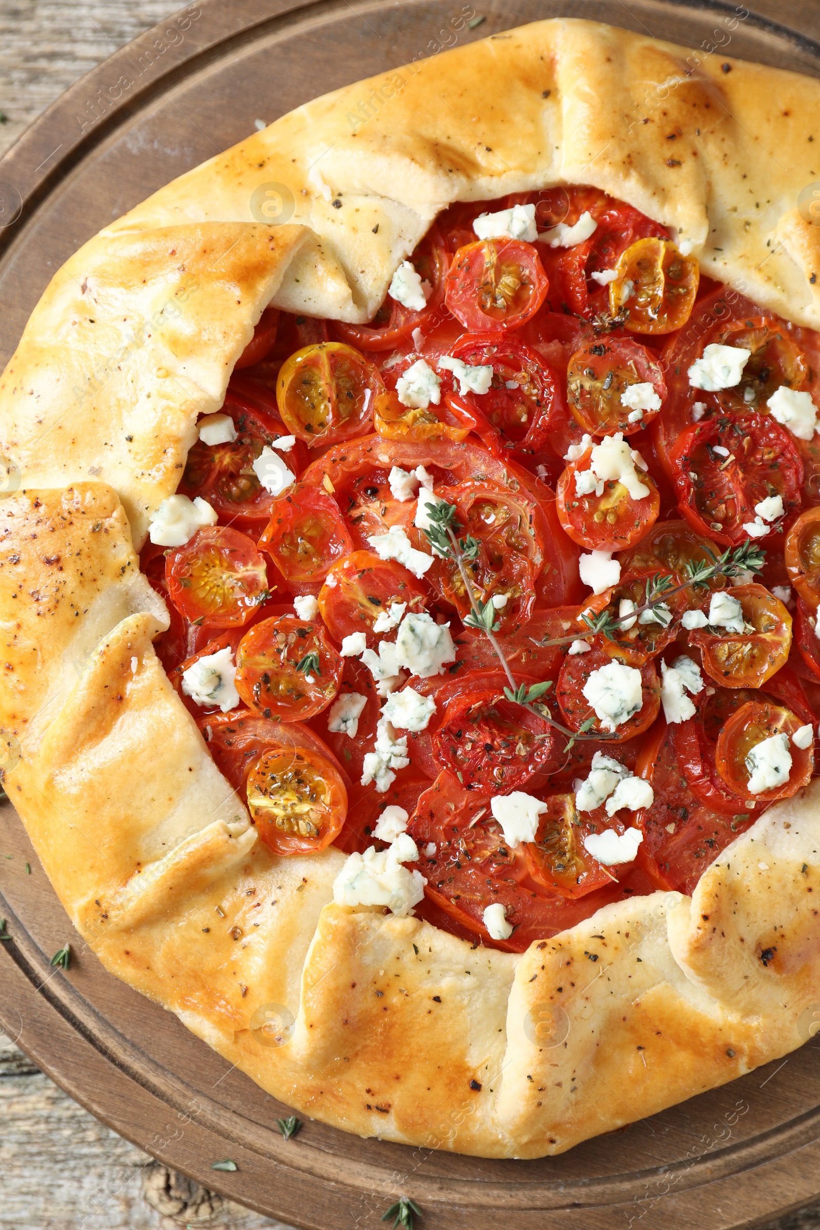 Photo of Tasty galette with tomato, thyme and cheese (Caprese galette) on wooden table, top view