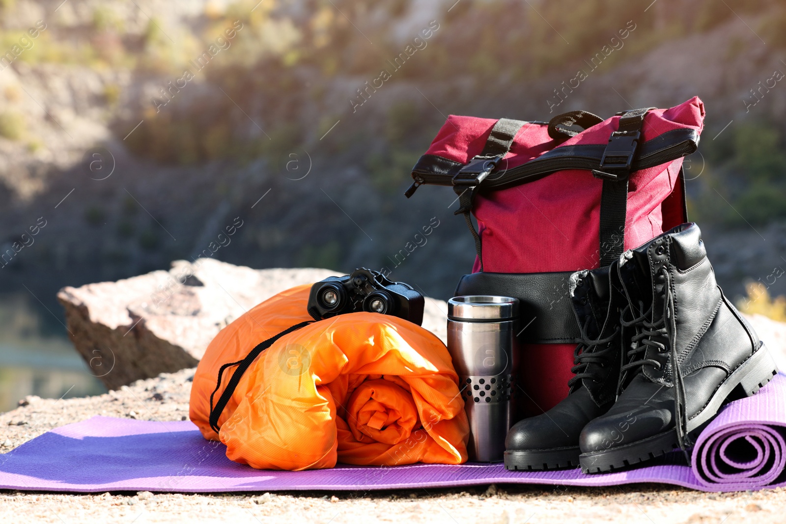 Photo of Set of camping equipment with sleeping bag on ground outdoors