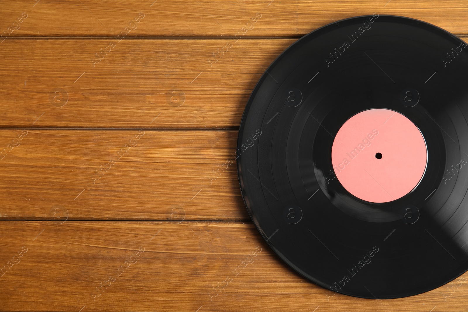 Photo of Vintage vinyl record on wooden table, top view. Space for text
