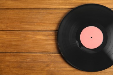 Photo of Vintage vinyl record on wooden table, top view. Space for text