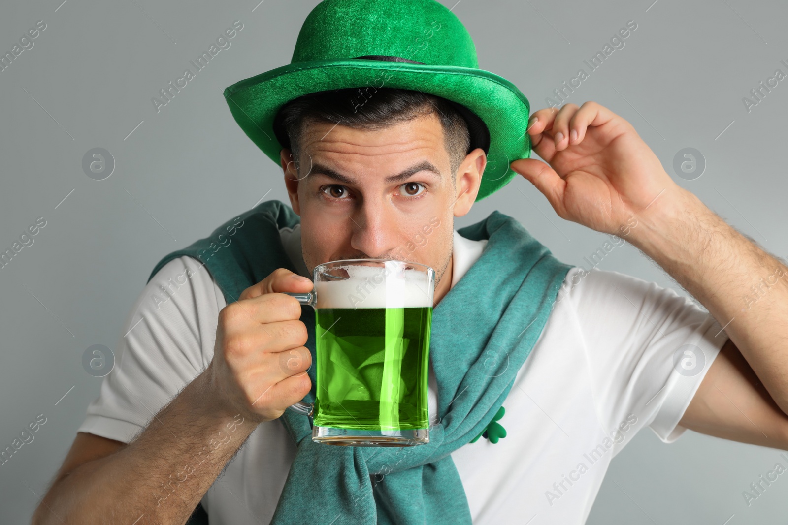 Photo of Man in St Patrick's Day outfit drinking beer on light grey background