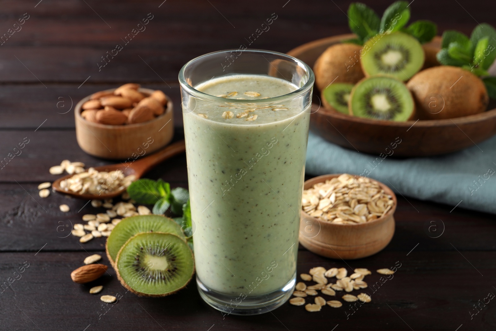 Photo of Glass of tasty kiwi smoothie with oatmeal on wooden table