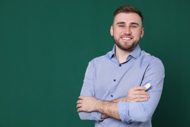 Photo of Portrait of young teacher with chalk on green background. Space for text