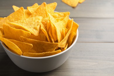 Tortilla chips (nachos) in bowl on wooden table, closeup