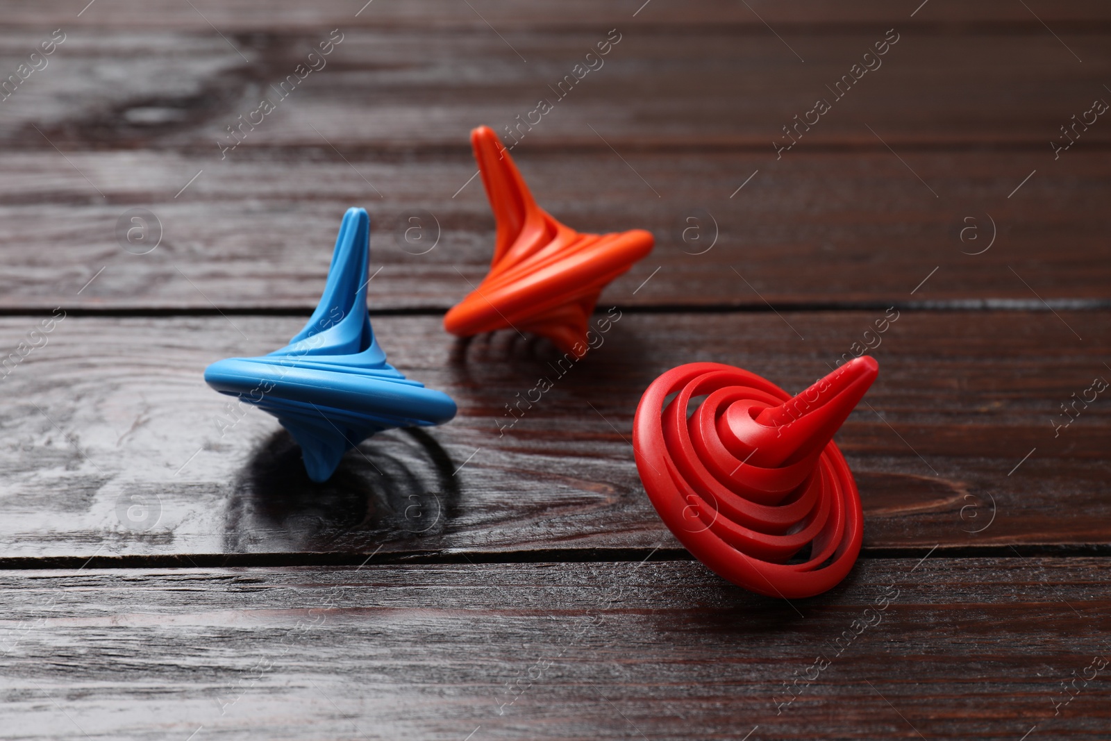 Photo of Bright spinning tops on wooden table, closeup