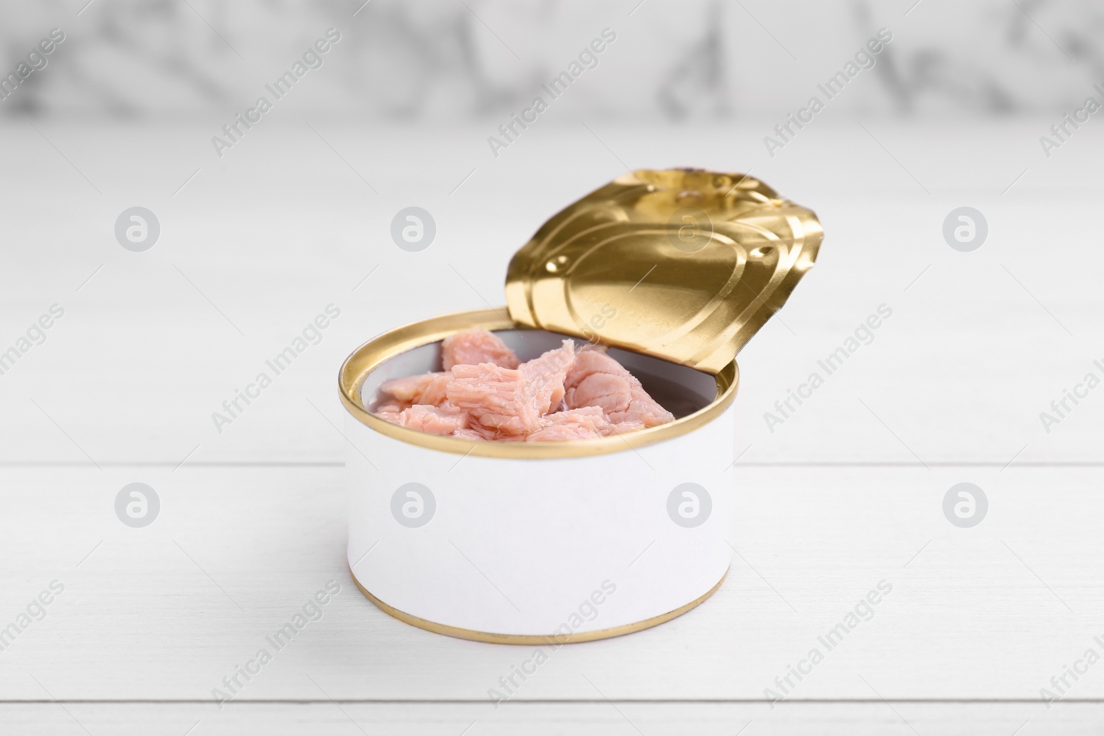 Photo of Tin can with canned tuna on white table, closeup