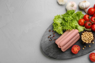Photo of Fresh raw vegetarian sausages and vegetables on grey table, flat lay. Space for text