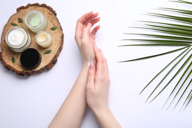 Photo of Woman applying hand cream on white background, top view