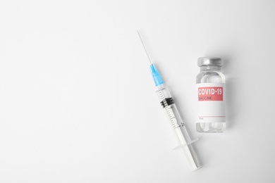 Photo of Vial with coronavirus vaccine and syringe on white background, flat lay. Space for text