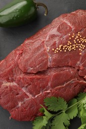 Photo of Piece of raw beef meat, parsley, mustard seeds and pepper on black table, above view