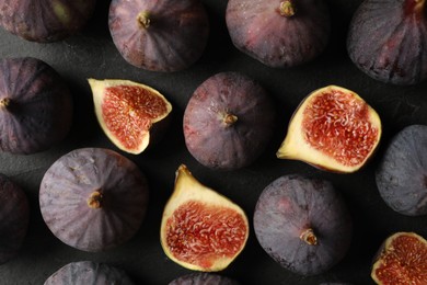 Tasty cut and whole figs on black table, flat lay