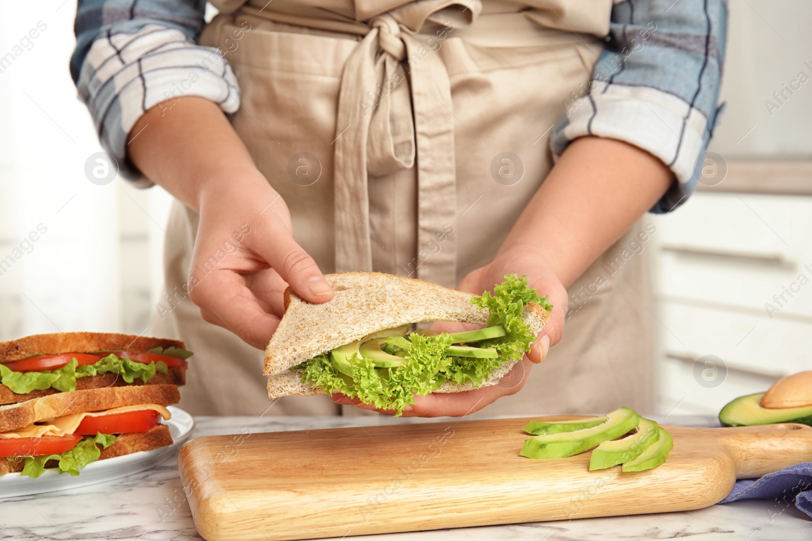 Photo of Woman making tasty sandwich at white marble table, closeup